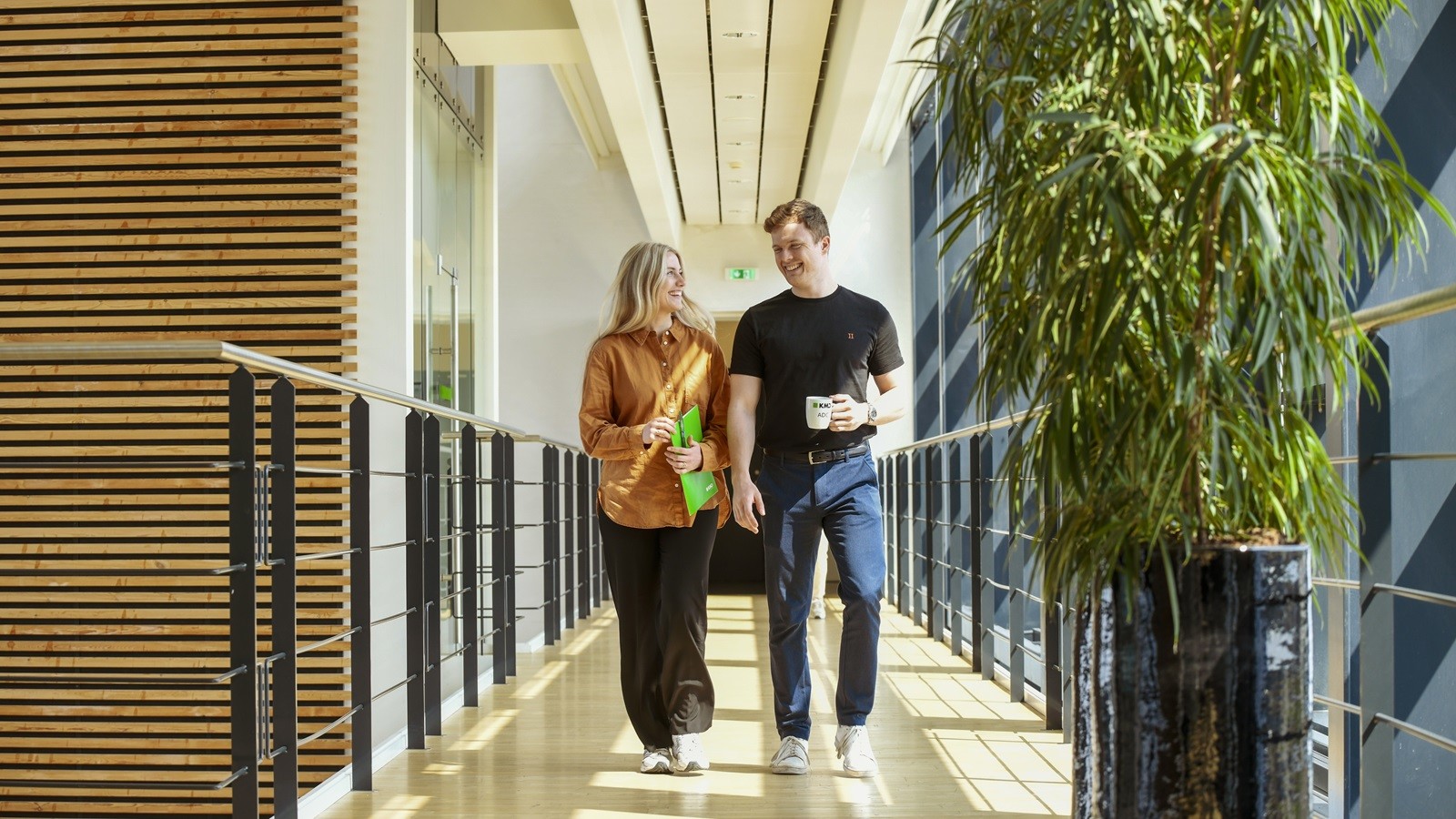 Two colleagues walking on a bridged hallway in KMD Aarhus office