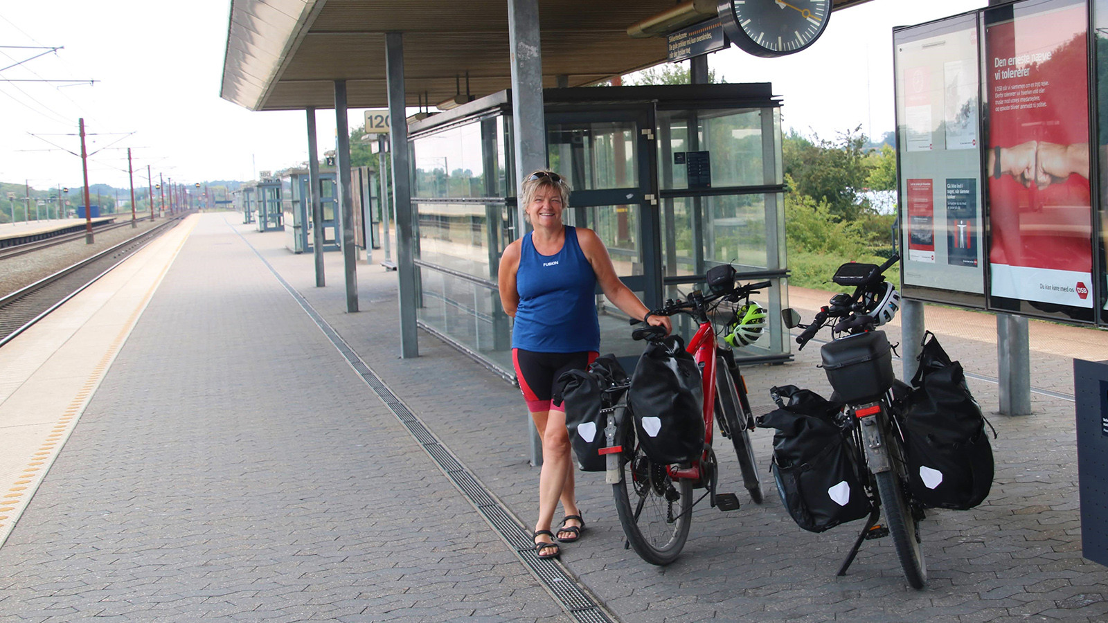 Kvinde i cykeltøj, der står på en s-tog perron med to cykler