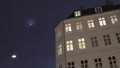 Hus med tændte vinduer mod en nattehimmel