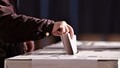 Mand der afgiver sin valgstemme, beskåret med fokus på hånden og valgstemmen