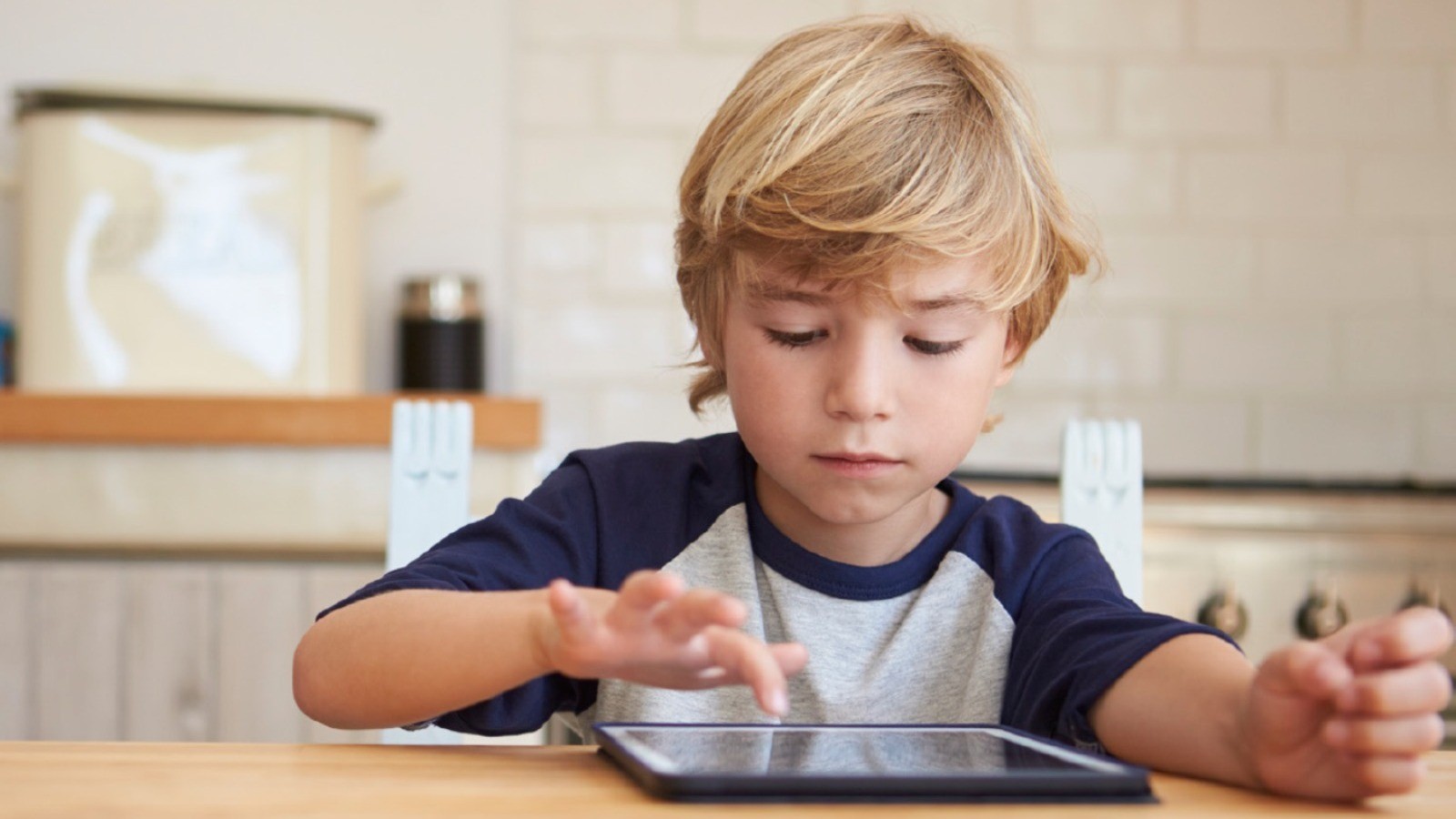 Barn, der interagerer med en tablet, der ligger på bordet