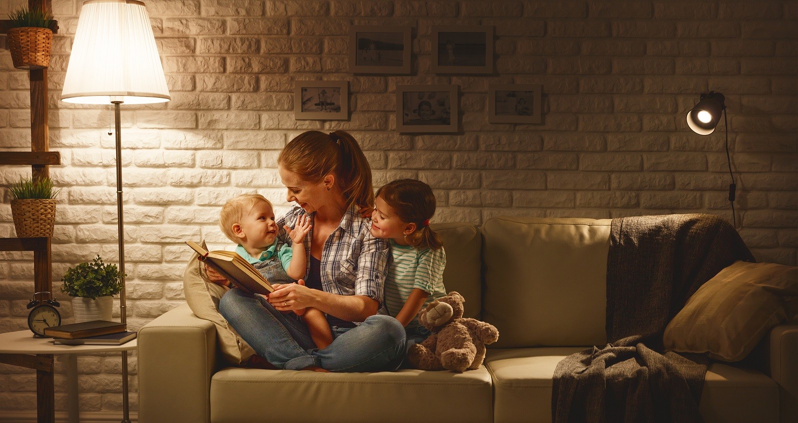 Mor der sidder i sofa med sine to børn, som hun læser op for