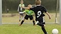 Dreng lægger an til at sparke en fodbold i mål