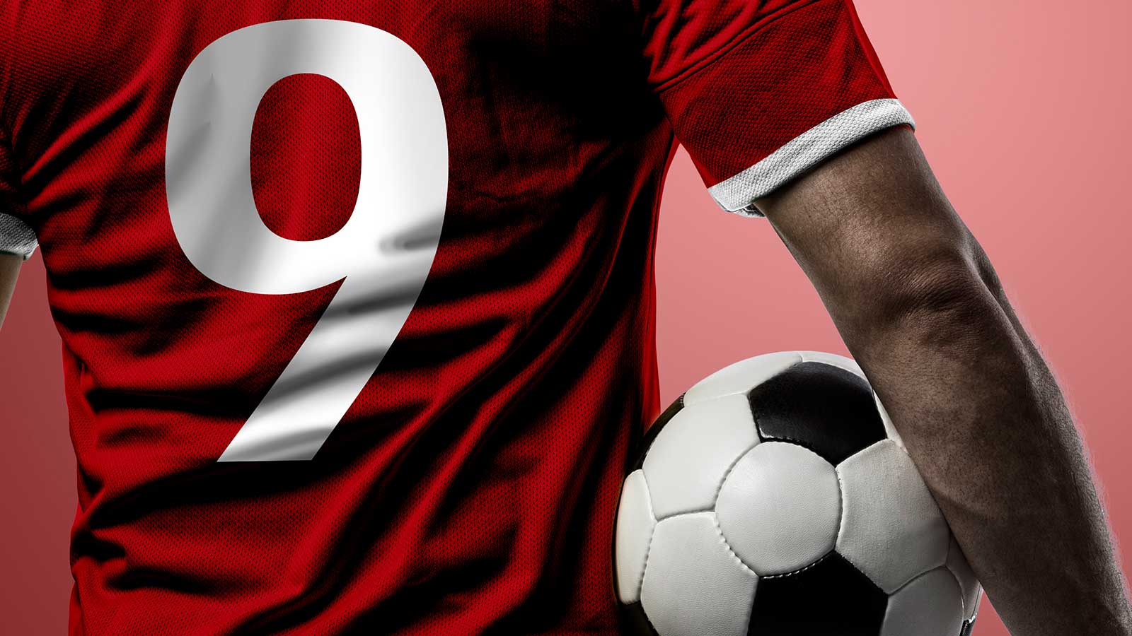 Fodboldspiller med rød trøjer holder bold under armen