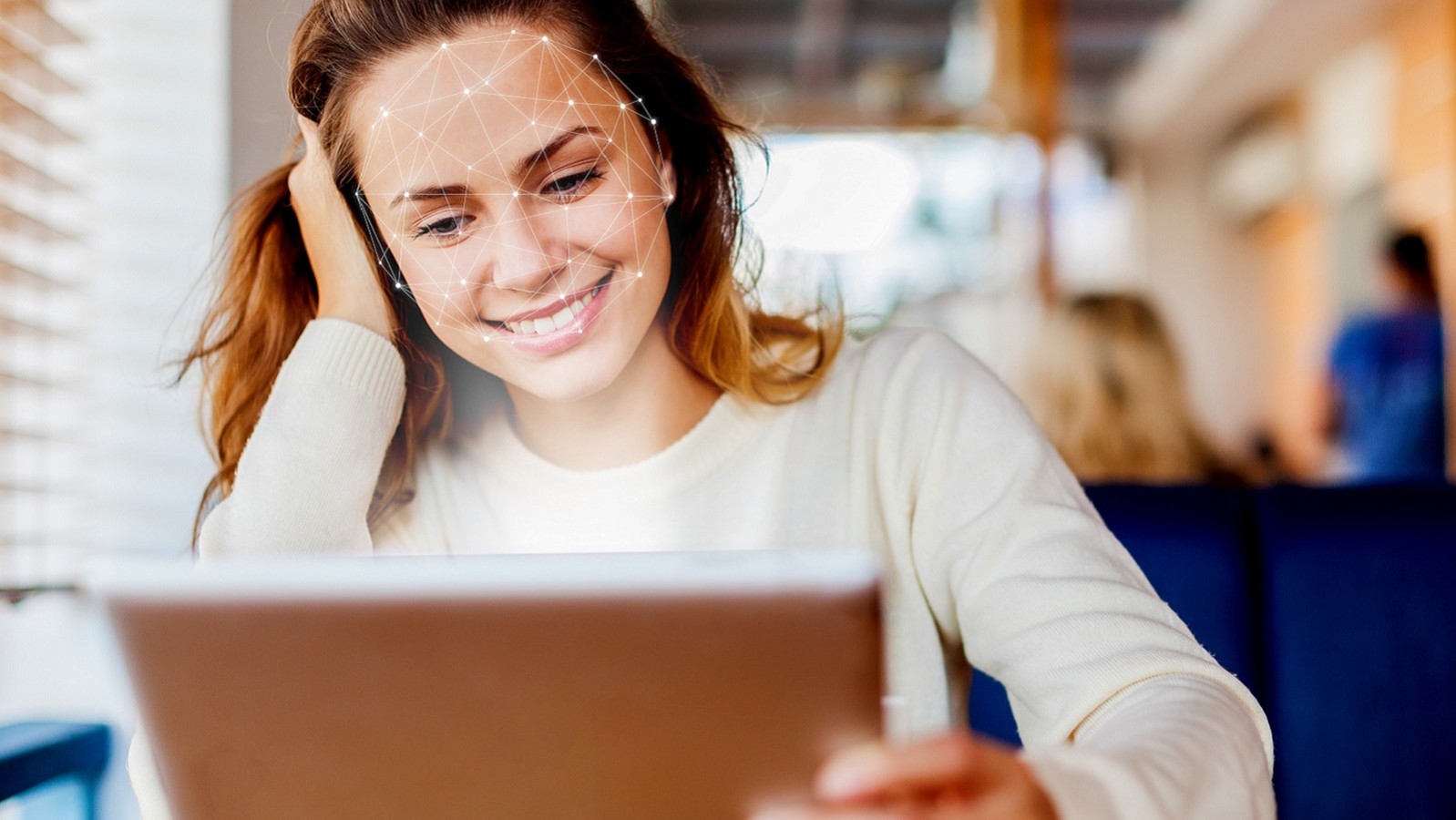 Smilende kvinde foran iPad med grafik af ansigtsscanning i ansigtet