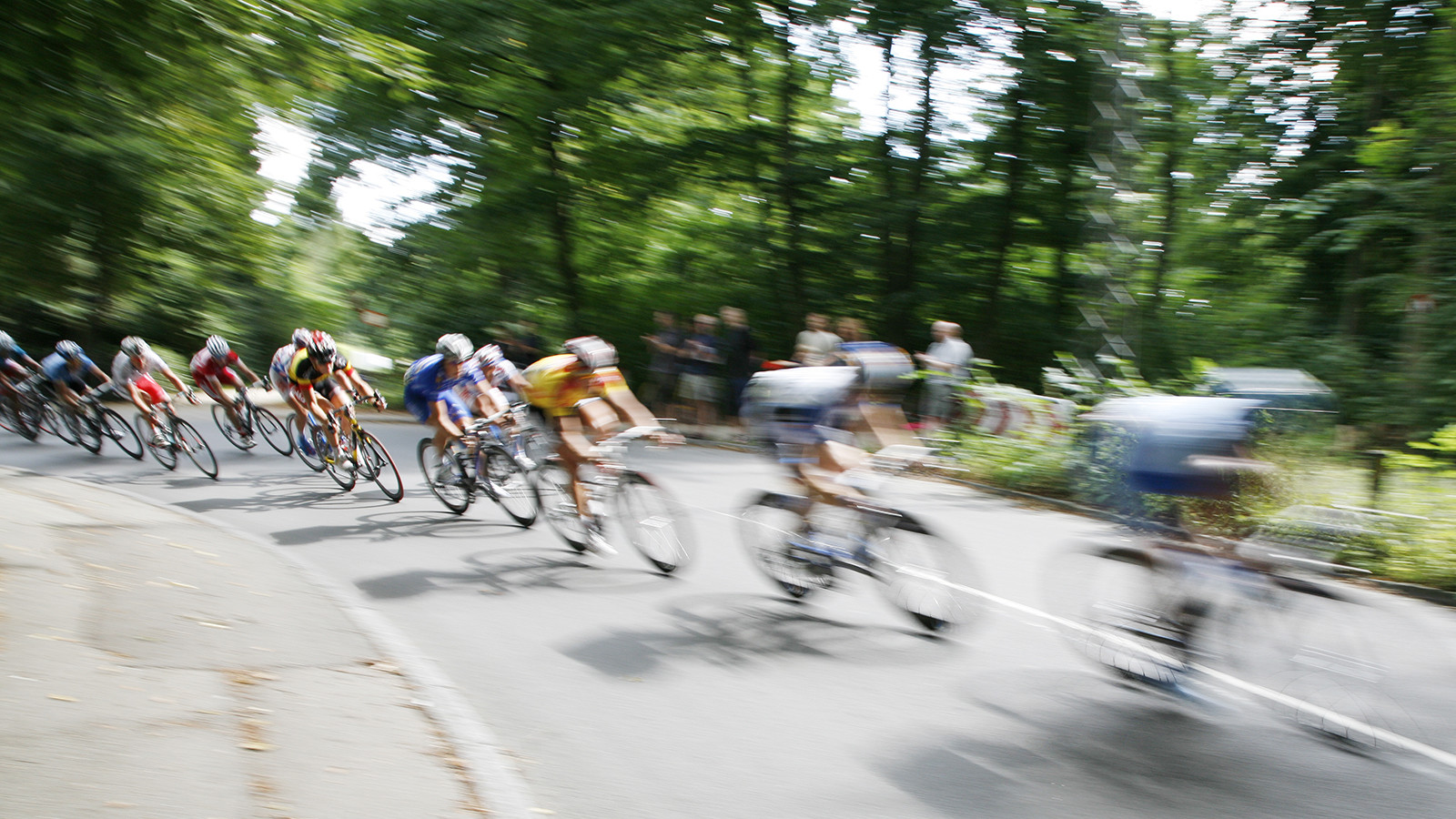 Forbipasserende cykelryttere med bevægelsessløring, som cykler på vejen i et skovområde