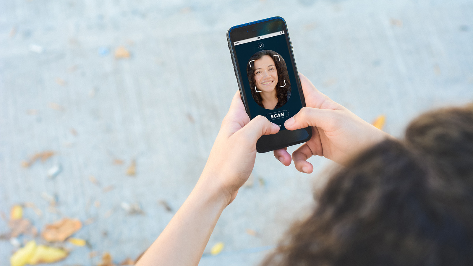 Person der holder smartphone med ansigtsgenkendelse, hvor man kan se personens ansigt