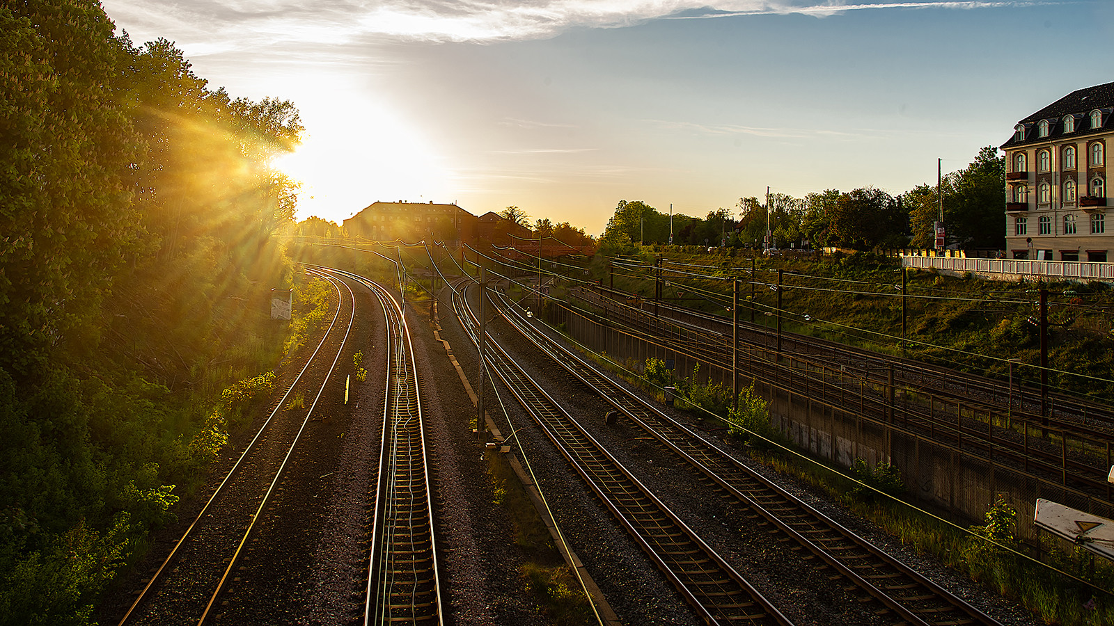 Rækker af togskinner med solopgang i baggrunden